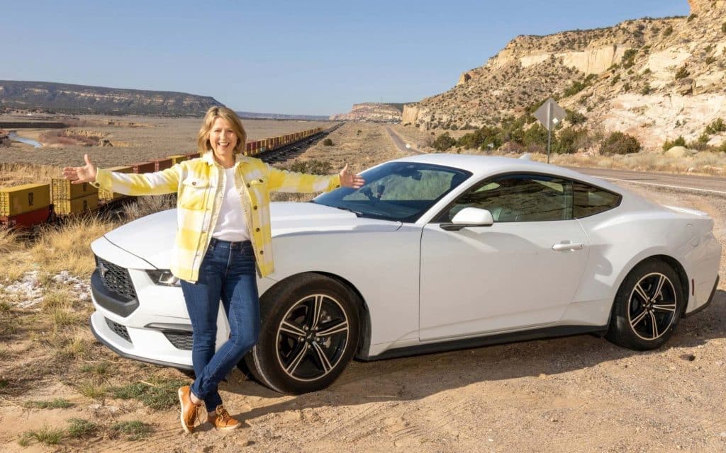 Samantha Brown in front of her Ford Mustang on Route 66 in New Mexico